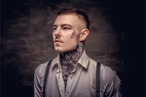 close up portrait young old fashioned tattooed guy wearing white shirt suspenders isolated dark background